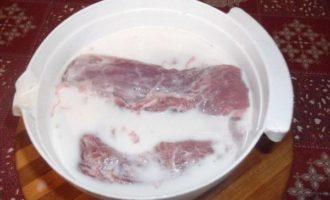 Нарежьте мясо на крупные куски, переложите на тарелку и залейте молоком. Оставьте это на кухонном столе.
